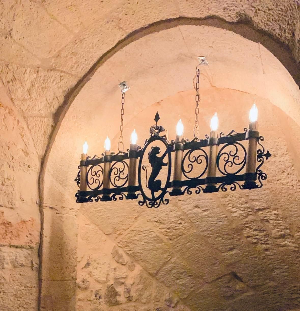 The iron chandelier beneath a stone arch.