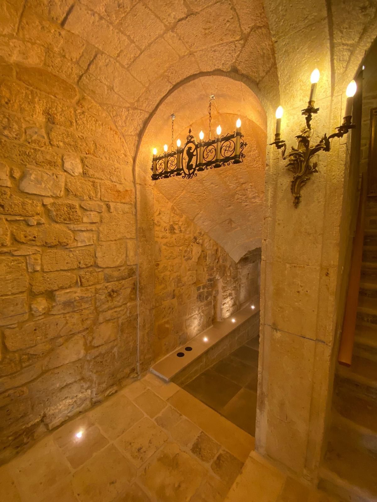 Candle sconces along the vaulted stone passage.