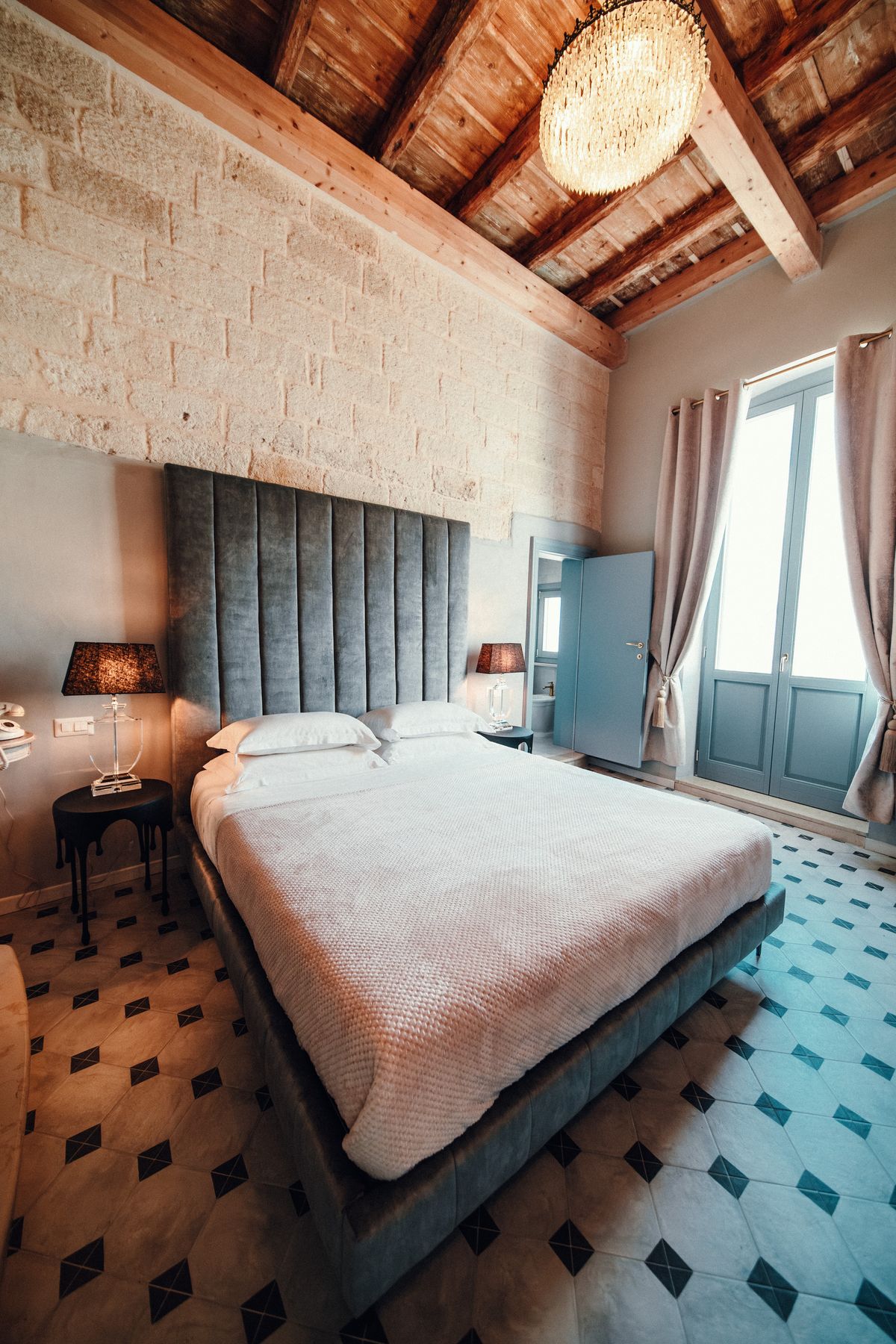 The bed under the beams, by the window.