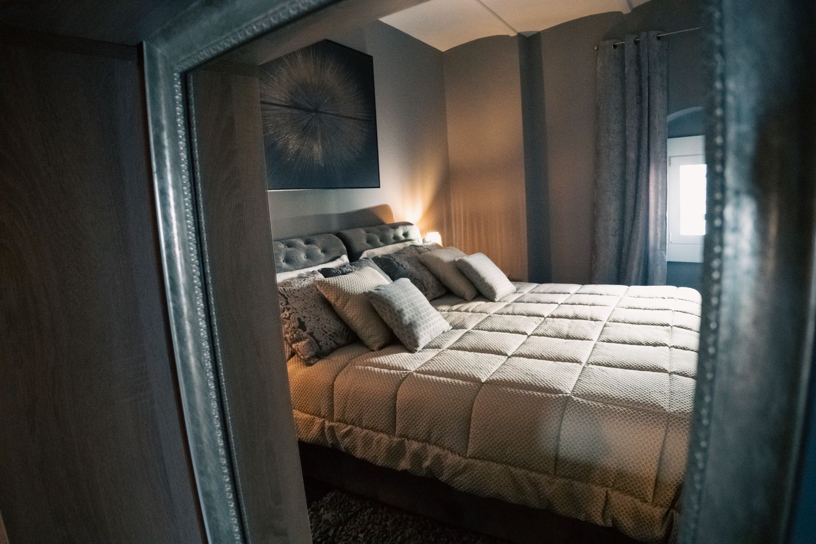 The quilted bed in the blue-grey bedroom.