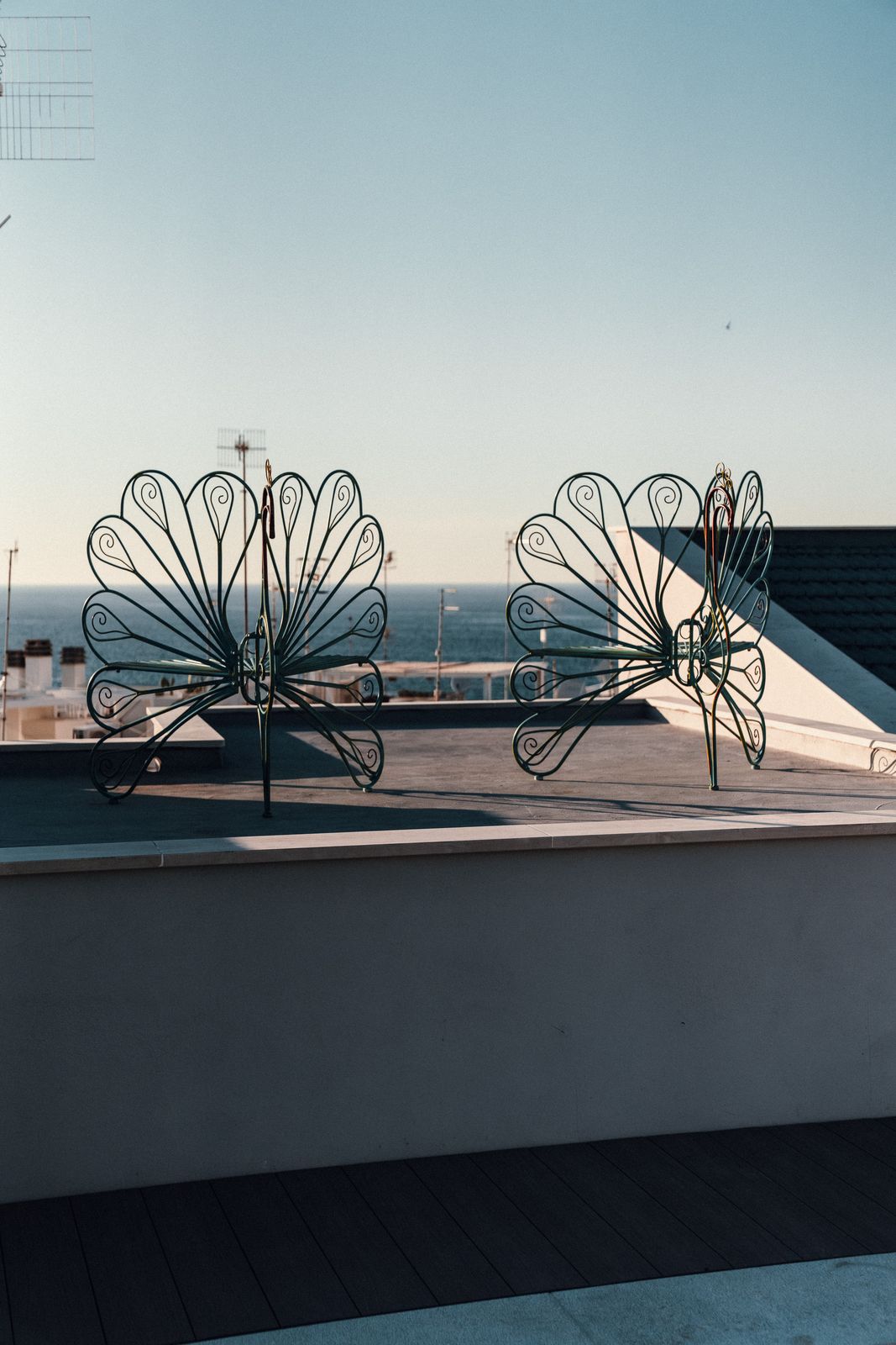Two wrought-iron peacock chairs on the rooftop, looking out over the Adriatic.