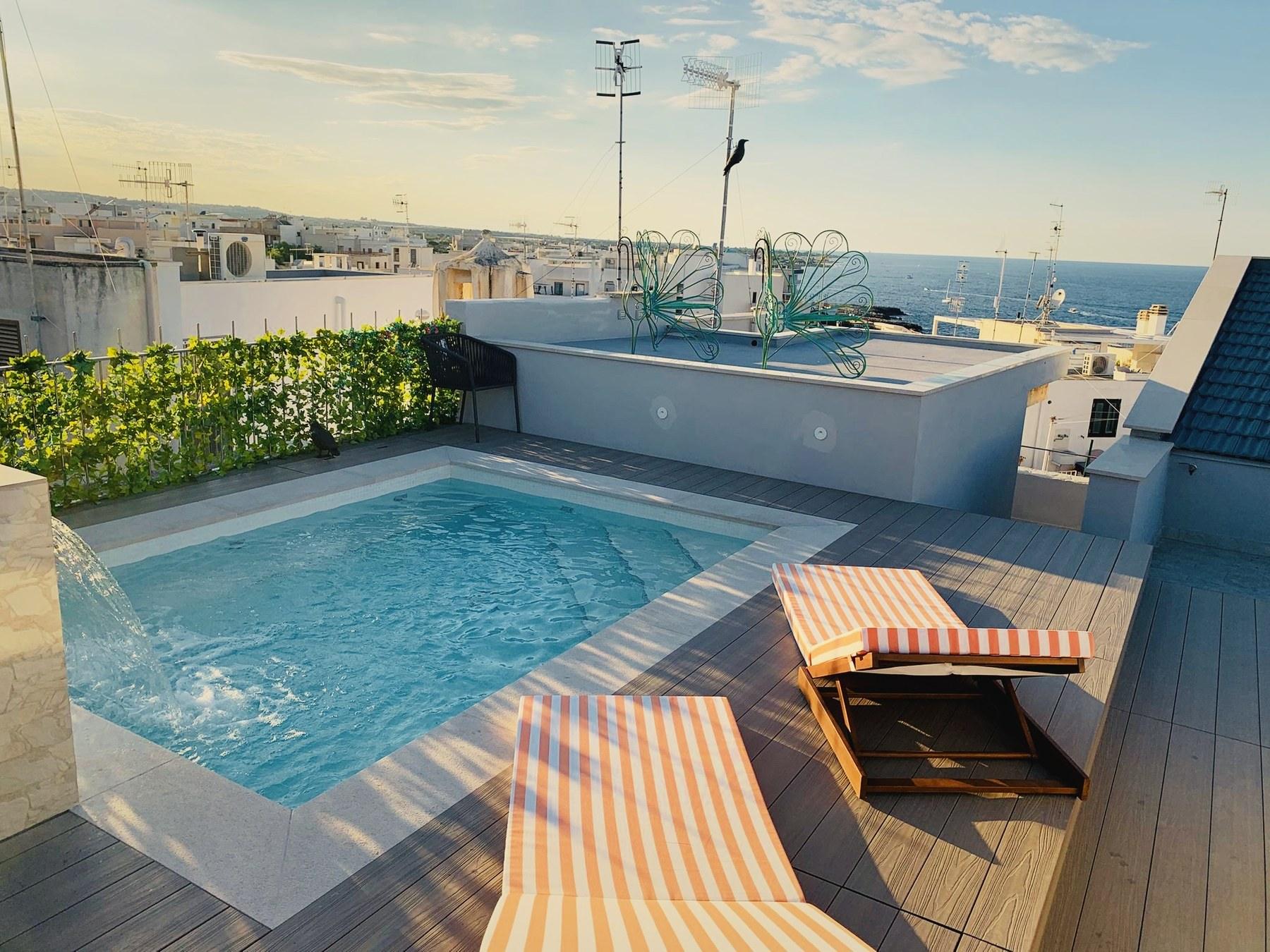 La piscina riscaldata sul tetto con la sua cascata, lettini sul deck e l'Adriatico oltre i tetti.